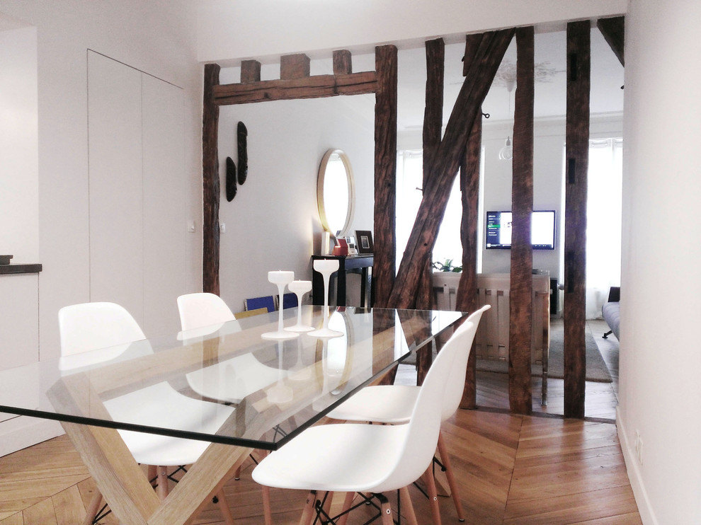 Immagine di una sala da pranzo aperta verso il soggiorno minimal con pareti bianche, parquet chiaro e nessun camino
