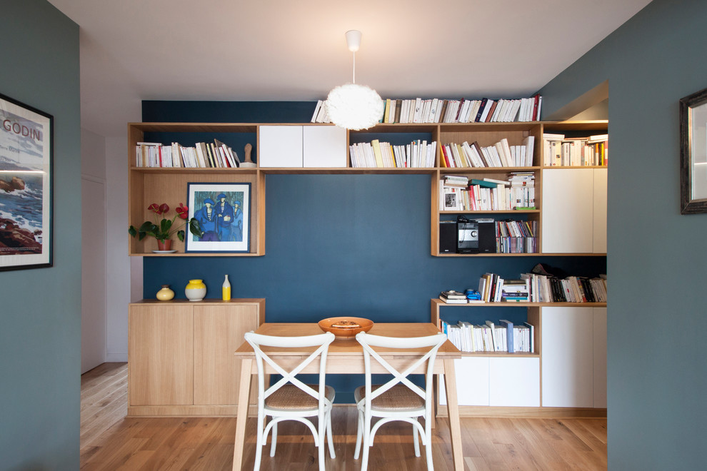 Small scandinavian dining room in Paris with blue walls and light hardwood flooring.