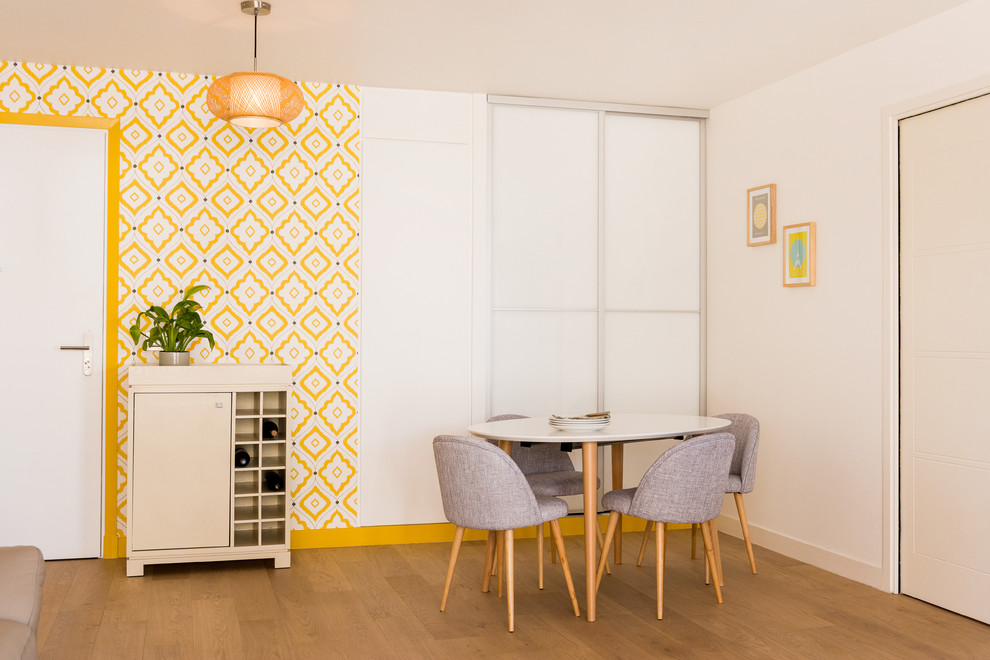 Large midcentury open plan dining room in Paris with yellow walls, light hardwood flooring and no fireplace.
