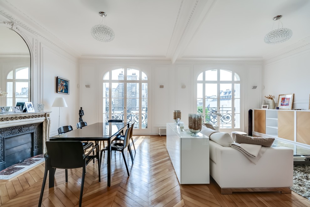 Mittelgroßes, Offenes Klassisches Esszimmer mit weißer Wandfarbe, braunem Holzboden und Kamin in Paris