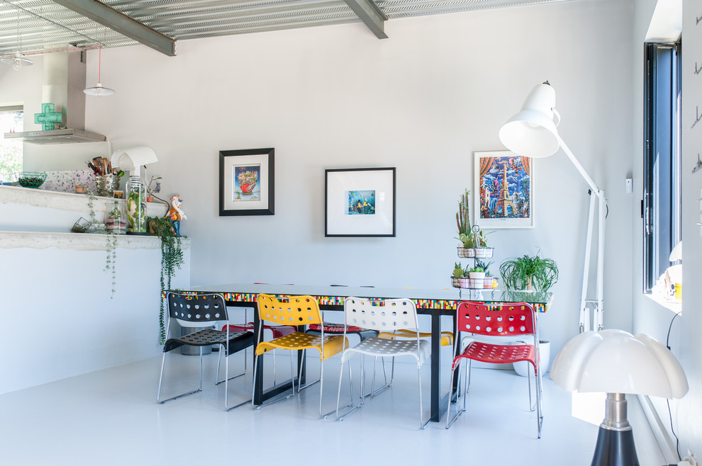Immagine di una sala da pranzo aperta verso il soggiorno industriale con pareti bianche e pavimento bianco