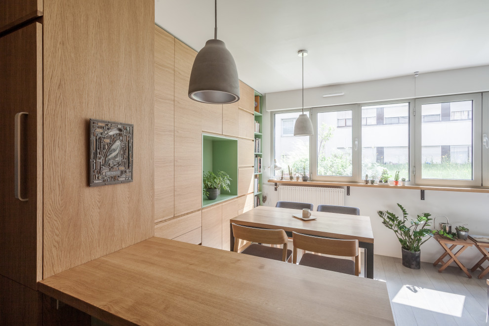 Immagine di una piccola sala da pranzo aperta verso la cucina nordica con pareti bianche, pavimento in legno verniciato, nessun camino, pavimento grigio e pareti in legno