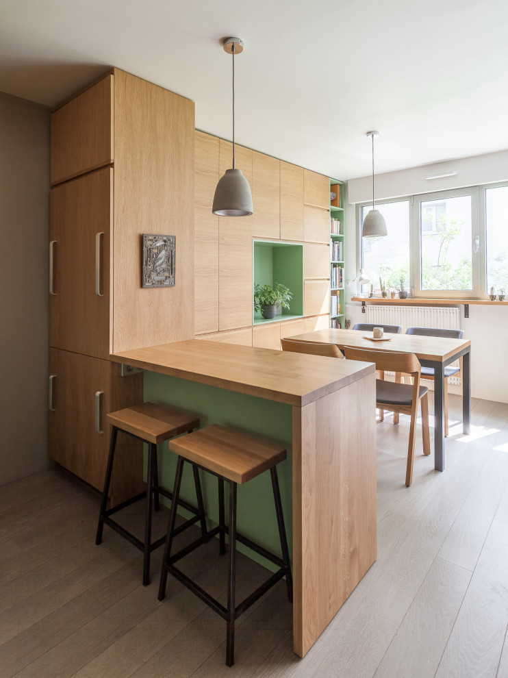 Kleine Skandinavische Wohnküche ohne Kamin mit weißer Wandfarbe, gebeiztem Holzboden, grauem Boden und Holzwänden in Paris