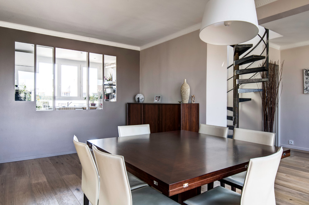 Photo of a contemporary dining room in Paris with grey walls and medium hardwood flooring.