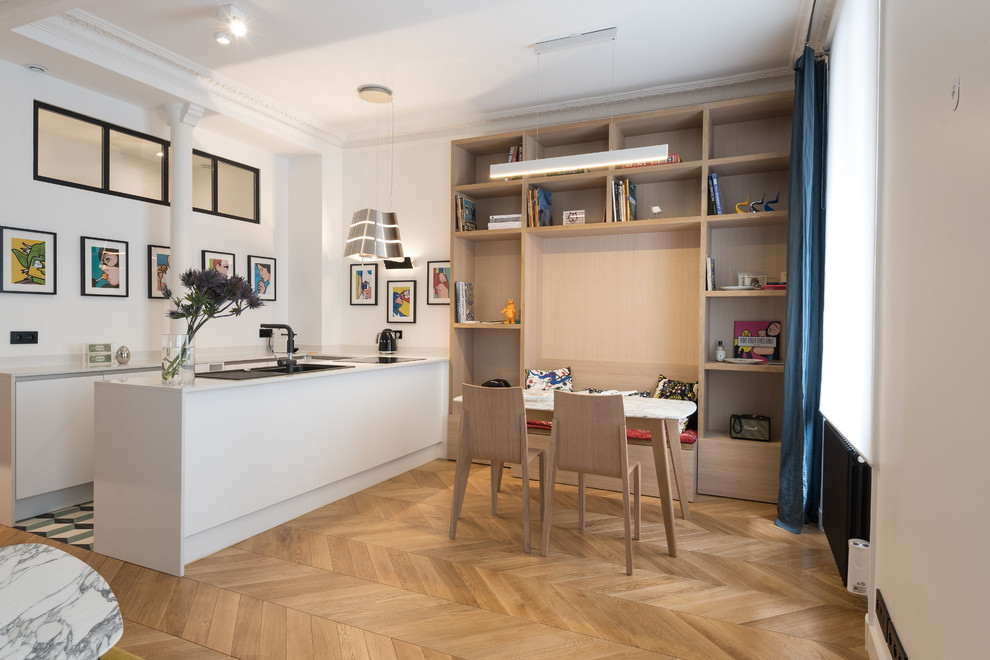 Aménagement d'une salle à manger ouverte sur la cuisine scandinave avec un mur blanc, parquet clair et un sol marron.