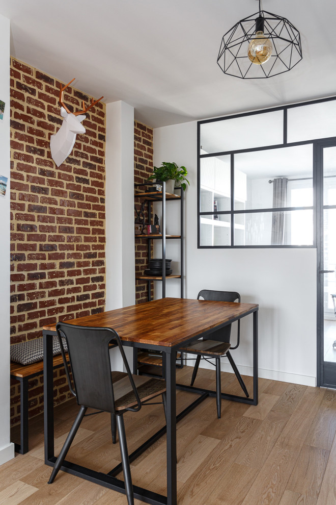 Photo of a small urban open plan dining room in Paris with white walls, light hardwood flooring, no fireplace, beige floors and brick walls.