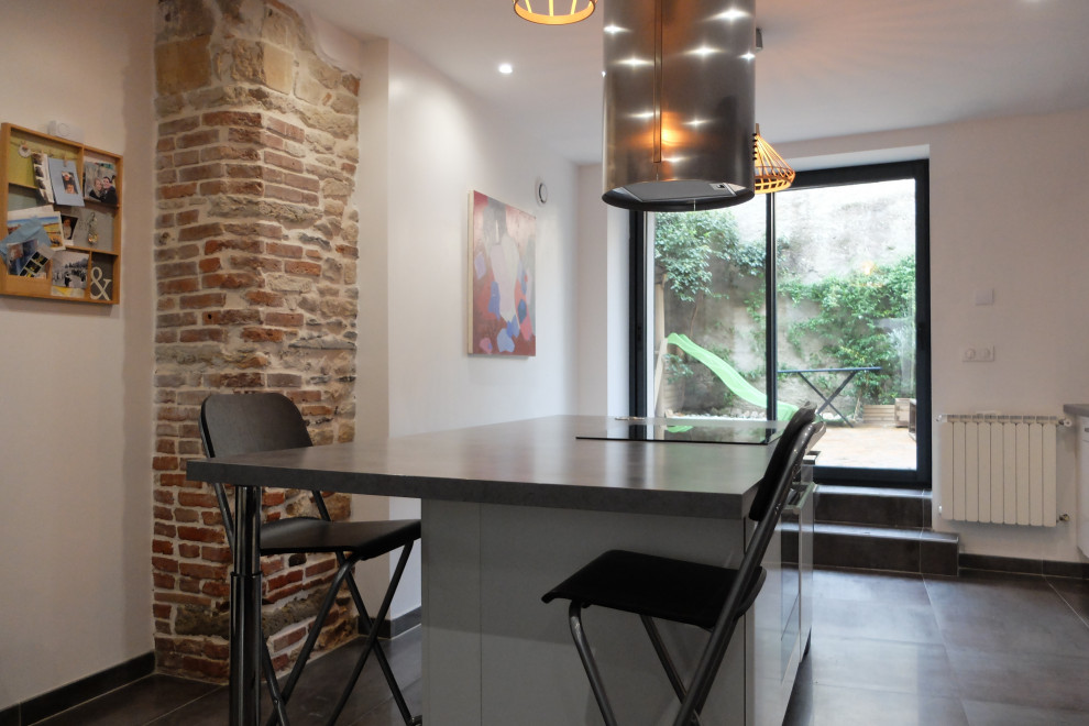 Immagine di una sala da pranzo aperta verso la cucina con pareti bianche, pavimento con piastrelle in ceramica, nessun camino e pavimento grigio