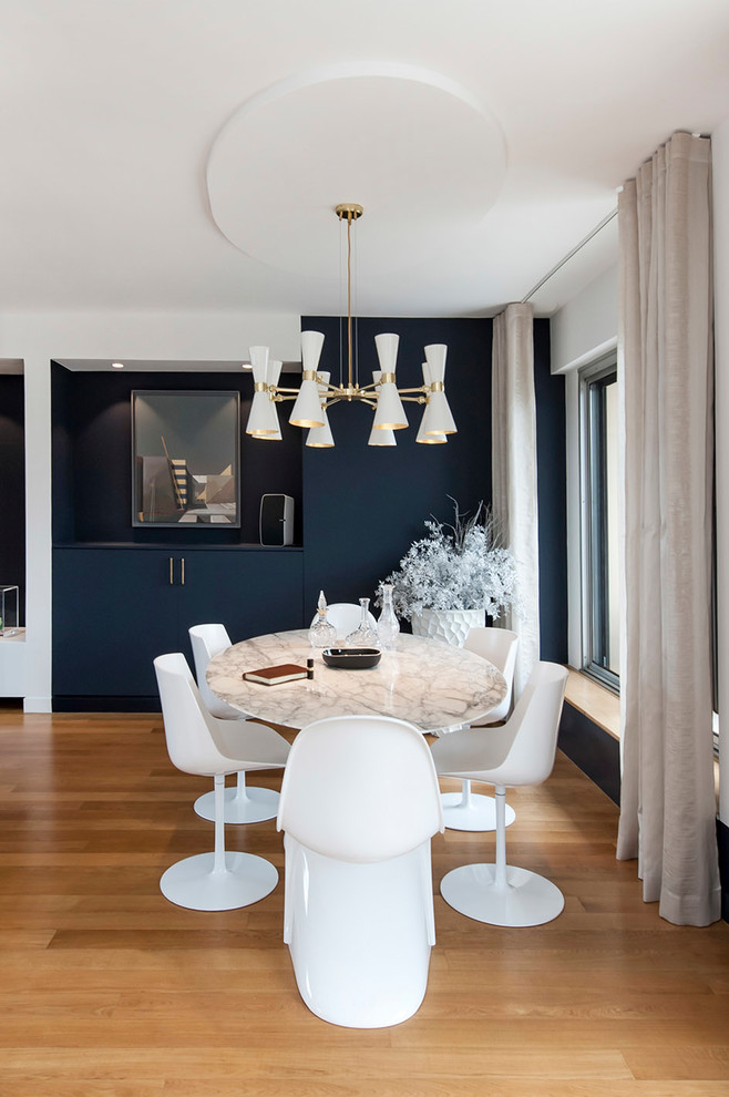 Photo of a large contemporary open plan dining room in Paris with blue walls, light hardwood flooring, a hanging fireplace, a plastered fireplace surround and beige floors.
