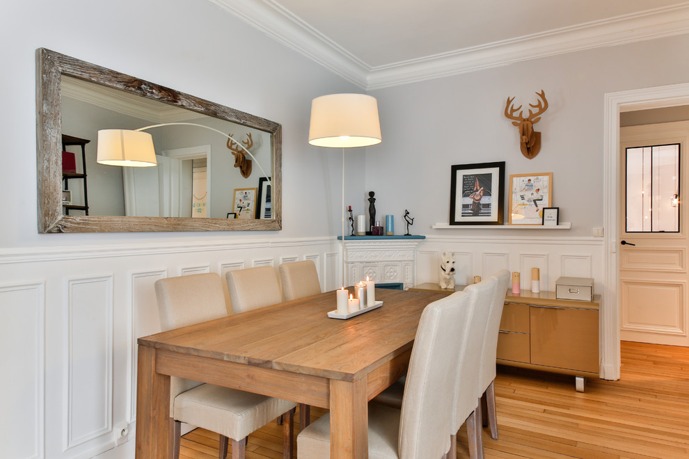 Cette image montre une grande salle à manger design avec un mur gris, parquet clair et un poêle à bois.