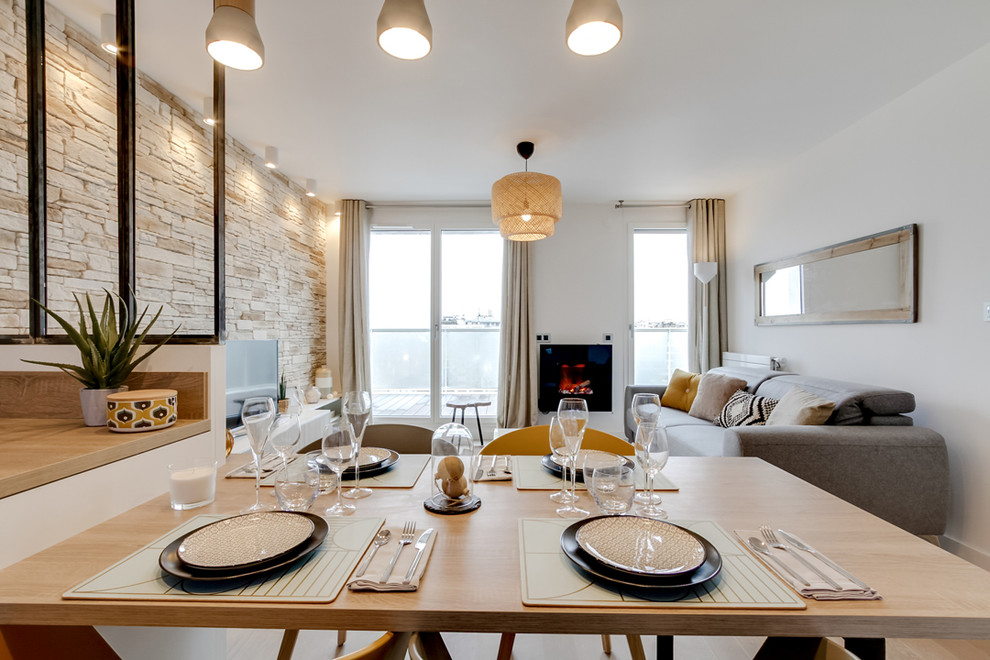 Idée de décoration pour une petite salle à manger ouverte sur la cuisine nordique avec un mur blanc, parquet clair, cheminée suspendue et un manteau de cheminée en métal.