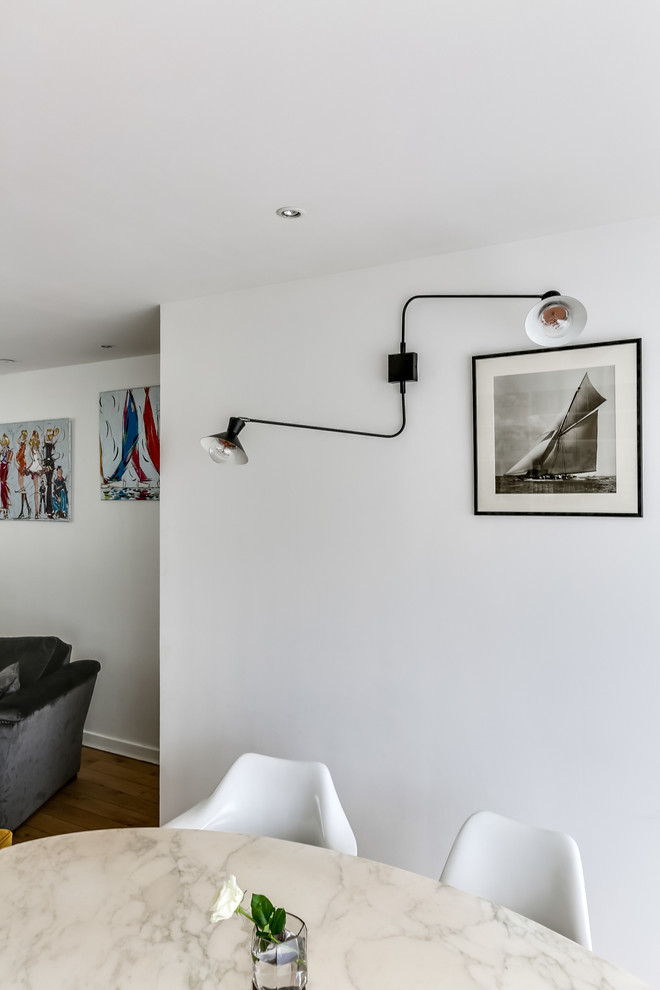 Cette image montre une salle à manger nordique avec un mur blanc et parquet clair.