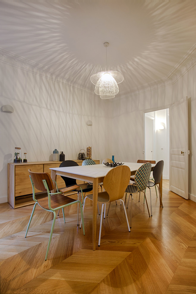 Cette photo montre une salle à manger ouverte sur le salon chic de taille moyenne avec un mur blanc, parquet clair et aucune cheminée.