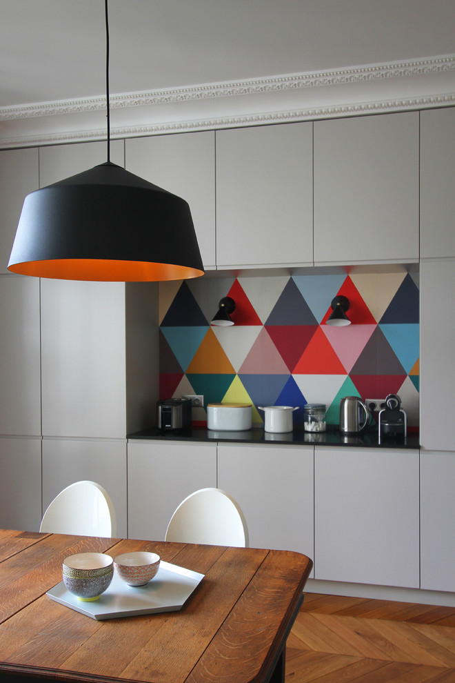 Стильный дизайн: кухня-столовая среднего размера в современном стиле с разноцветными стенами и паркетным полом среднего тона - последний тренд