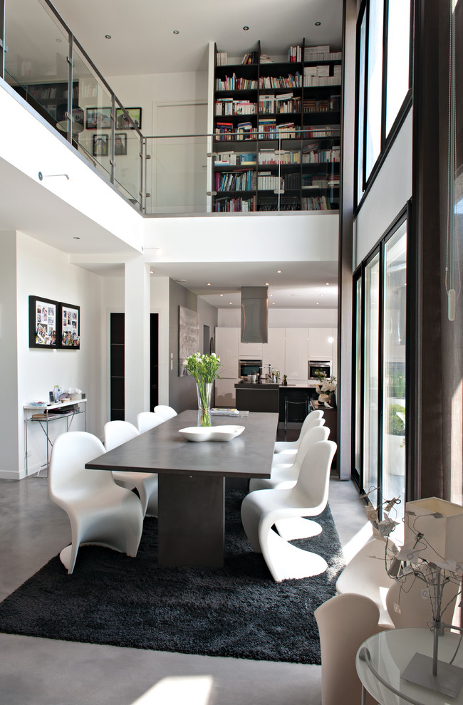 На фото: гостиная-столовая в современном стиле с белыми стенами и бетонным полом