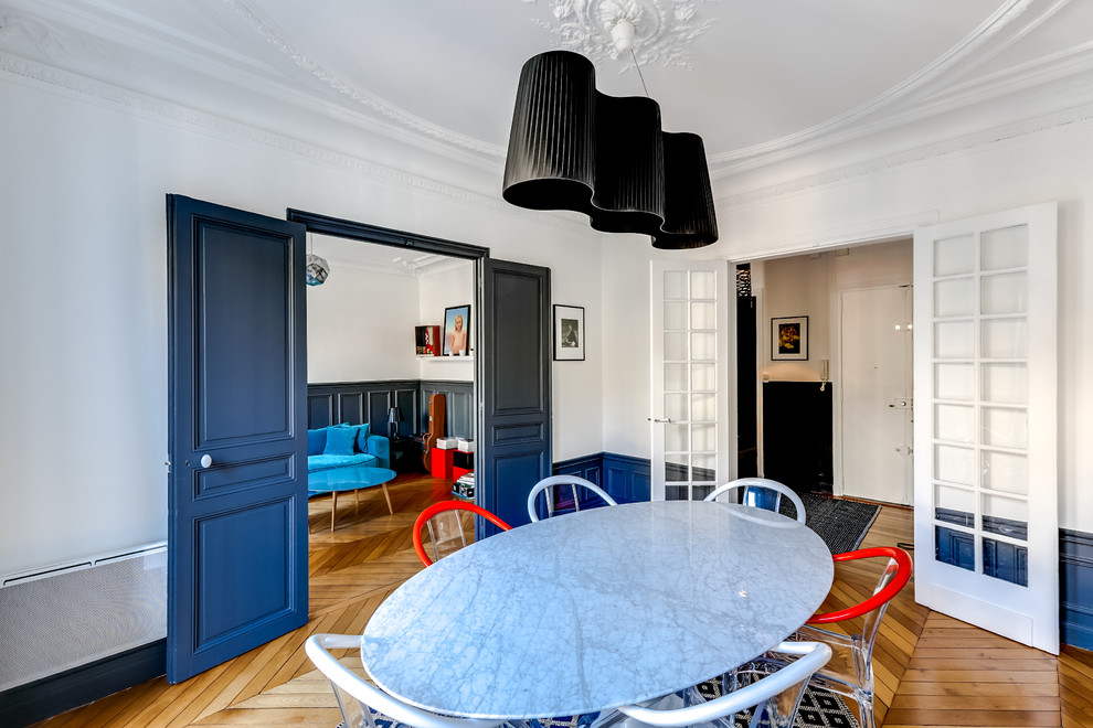 Cette image montre une salle à manger ouverte sur le salon design de taille moyenne avec un mur bleu, parquet clair et un sol beige.
