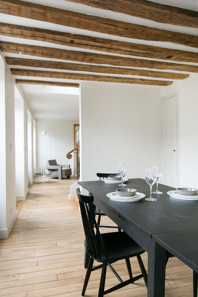 Cette photo montre une salle à manger ouverte sur le salon tendance de taille moyenne avec un mur blanc et parquet clair.