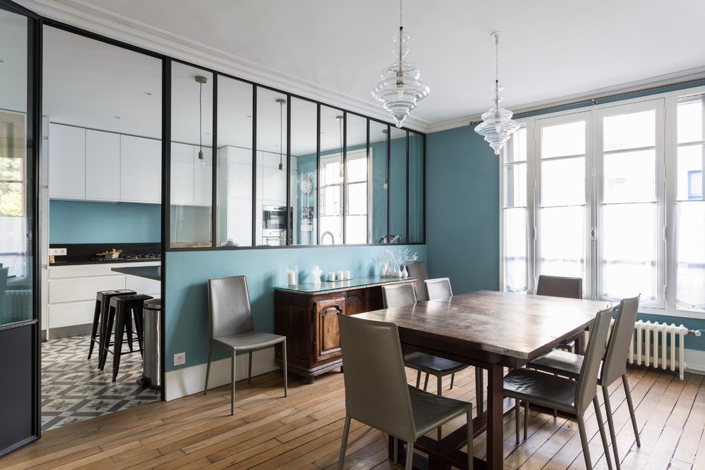Aménagement d'une grande salle à manger ouverte sur le salon contemporaine avec un mur bleu, un sol beige, un sol en bois brun et aucune cheminée.
