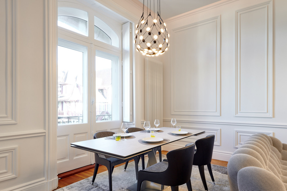 Idée de décoration pour une grande salle à manger ouverte sur le salon design avec un mur blanc, un sol en bois brun, un sol marron et boiseries.