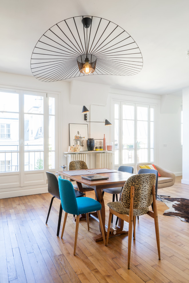 This is an example of a contemporary dining room in Paris with white walls and light hardwood flooring.