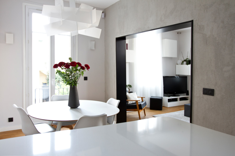 Cette photo montre une salle à manger ouverte sur la cuisine tendance de taille moyenne avec un mur gris, parquet clair et un sol beige.