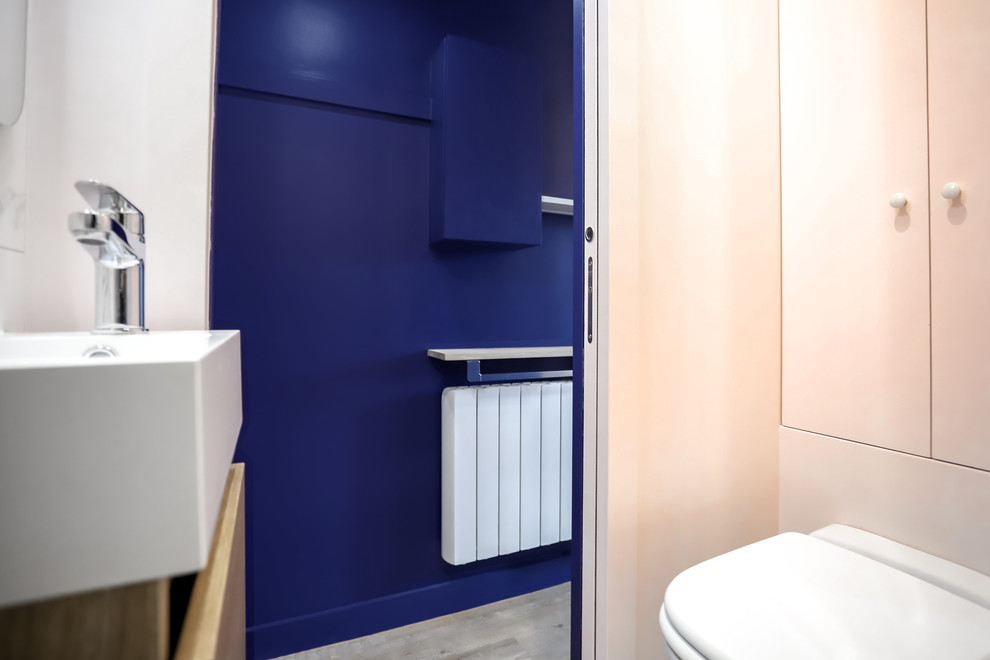 Inredning av ett litet badrum med dusch, med luckor med profilerade fronter, beige skåp, en kantlös dusch, en vägghängd toalettstol, grå kakel, marmorkakel, rosa väggar, marmorgolv, ett fristående handfat, bänkskiva i akrylsten, grått golv och dusch med gångjärnsdörr