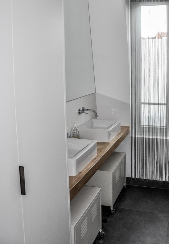 Cette image montre une salle de bain principale urbaine de taille moyenne avec un placard sans porte, un mur blanc, sol en béton ciré, un plan vasque, un plan de toilette en bois, un sol gris et un plan de toilette marron.