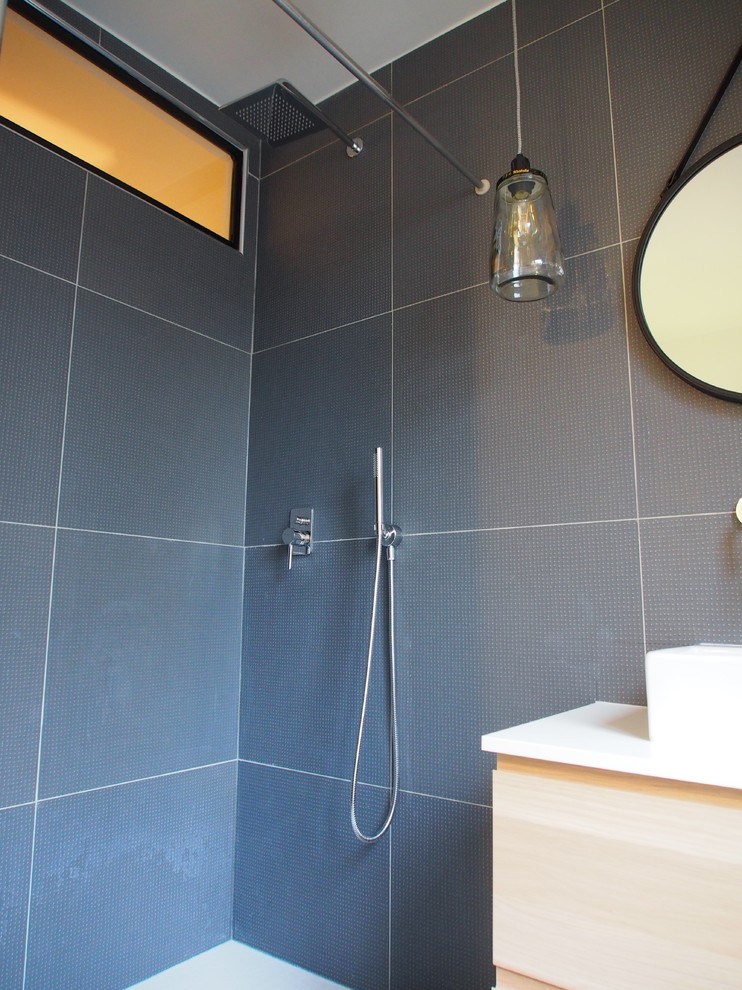 Idée de décoration pour une salle de bain principale design en bois clair de taille moyenne avec une douche à l'italienne, WC suspendus, un carrelage bleu, des carreaux de céramique, un mur blanc, un sol en carrelage de céramique, une vasque et un plan de toilette en stratifié.