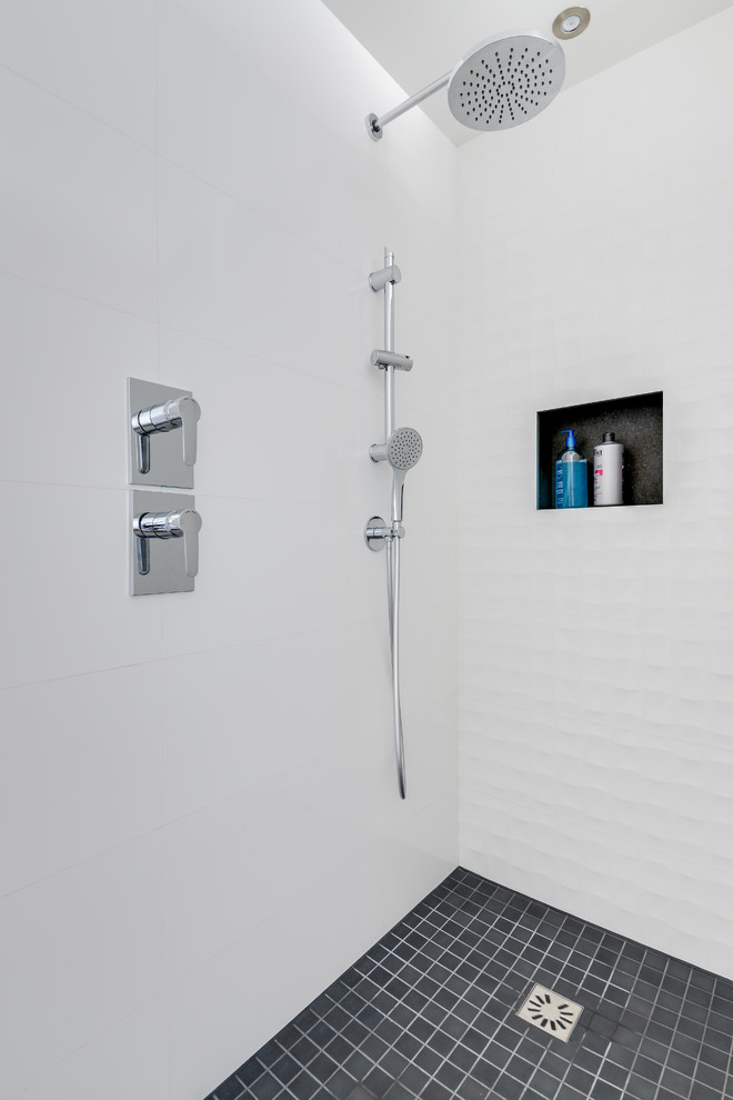 Cette image montre une douche en alcôve design avec un carrelage blanc, des carreaux de céramique, un mur blanc et un sol gris.