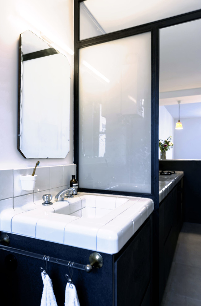 Inredning av ett modernt litet badrum med dusch, med luckor med profilerade fronter, en kantlös dusch, vit kakel, porslinskakel, klinkergolv i keramik, kaklad bänkskiva, ett integrerad handfat och vita väggar