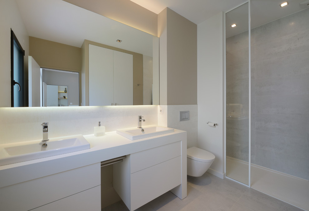 На фото: ванная комната среднего размера в современном стиле с душевой кабиной, душем в нише, инсталляцией, серой плиткой, врезной раковиной и бежевыми стенами с