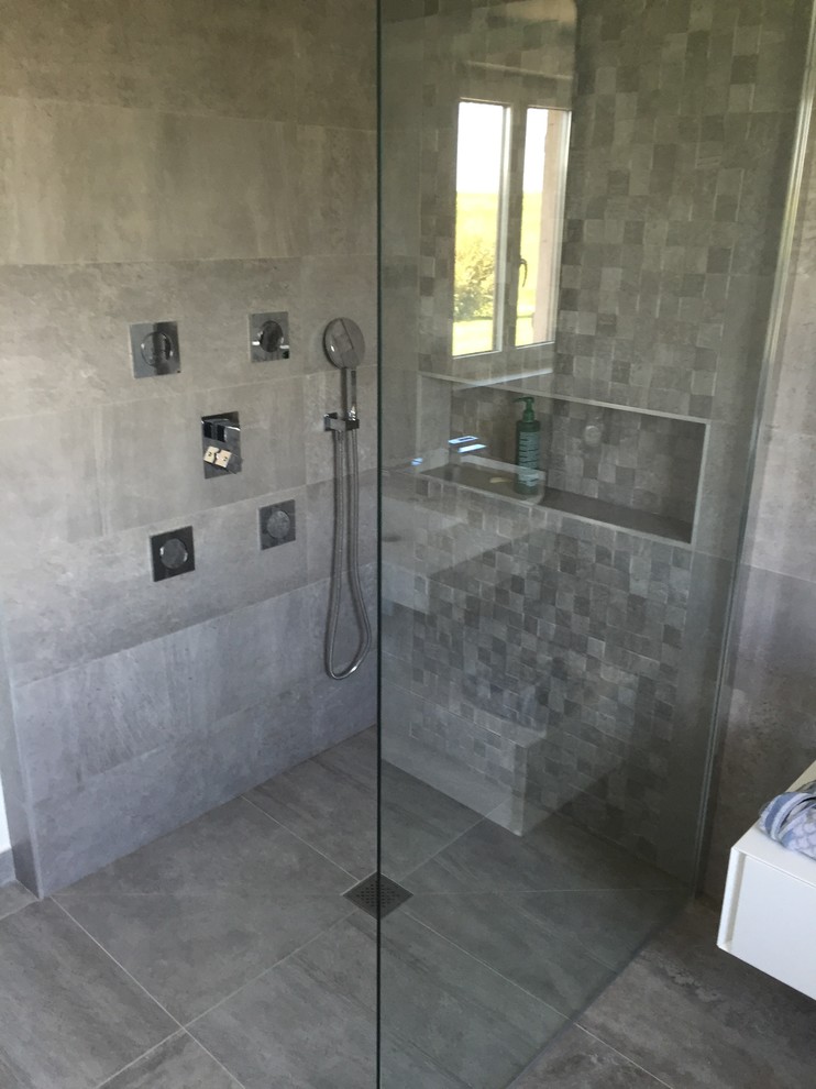 Cette image montre une grande salle de bain principale design avec une baignoire encastrée, une douche à l'italienne, un carrelage gris, des carreaux de céramique, un mur gris, un sol en carrelage de céramique et un plan vasque.