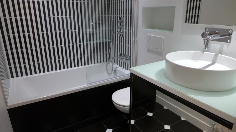 Inspiration pour une salle de bain principale design de taille moyenne avec un combiné douche/baignoire, WC suspendus, un carrelage blanc, un carrelage noir, un mur blanc, un sol en carrelage de porcelaine, un lavabo posé et un sol noir.