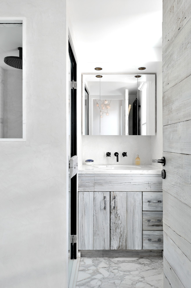 Réalisation d'une salle de bain design avec un placard à porte plane, des portes de placard grises, un mur blanc, un lavabo encastré et un sol gris.