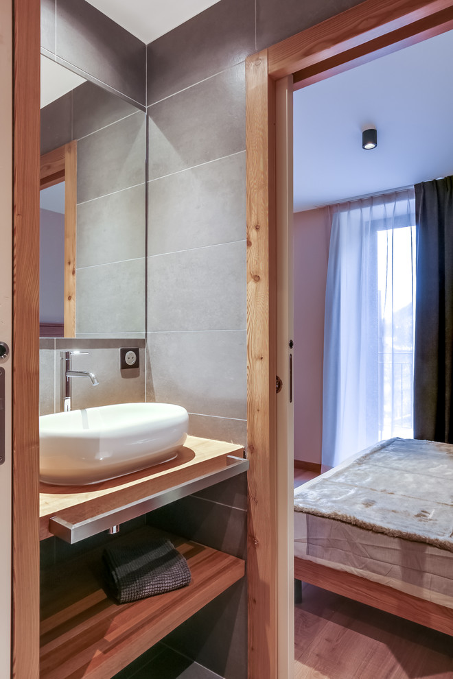Ispirazione per una stanza da bagno padronale design di medie dimensioni con doccia aperta, piastrelle grigie, piastrelle in ceramica, pareti grigie, pavimento in ardesia, lavabo a consolle e top in legno