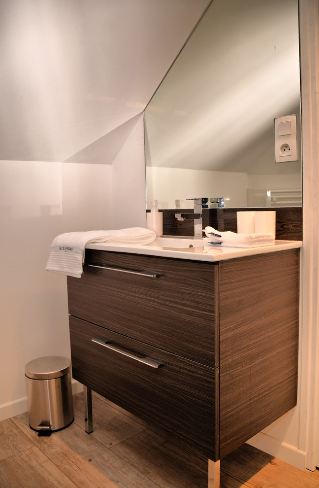 Exemple d'une petite salle d'eau tendance en bois foncé avec un mur blanc, sol en stratifié, un plan de toilette en surface solide, un placard à porte plane, un lavabo posé, un sol beige et un plan de toilette blanc.