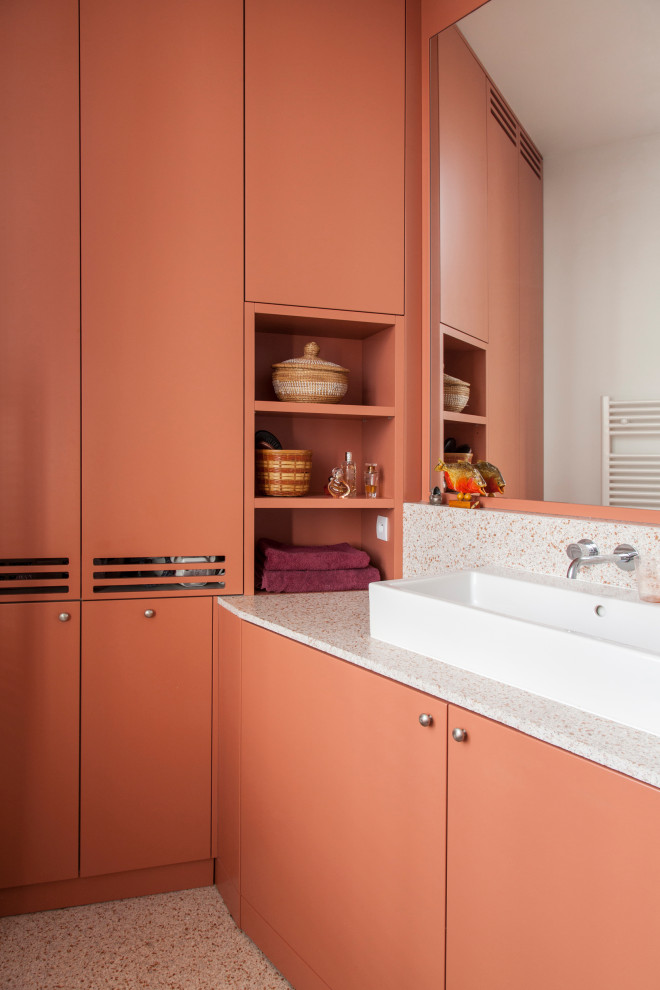 Modernes Badezimmer mit flächenbündigen Schrankfronten, orangefarbenen Schränken, oranger Wandfarbe, Aufsatzwaschbecken, beigem Boden und weißer Waschtischplatte in Paris