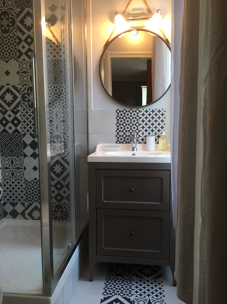 パリにある小さなミッドセンチュリースタイルのおしゃれなバスルーム (浴槽なし) (コーナー設置型シャワー、コンソール型シンク、木製洗面台、白い床、引戸のシャワー、茶色いキャビネット、壁掛け式トイレ、グレーの壁、セラミックタイルの床) の写真