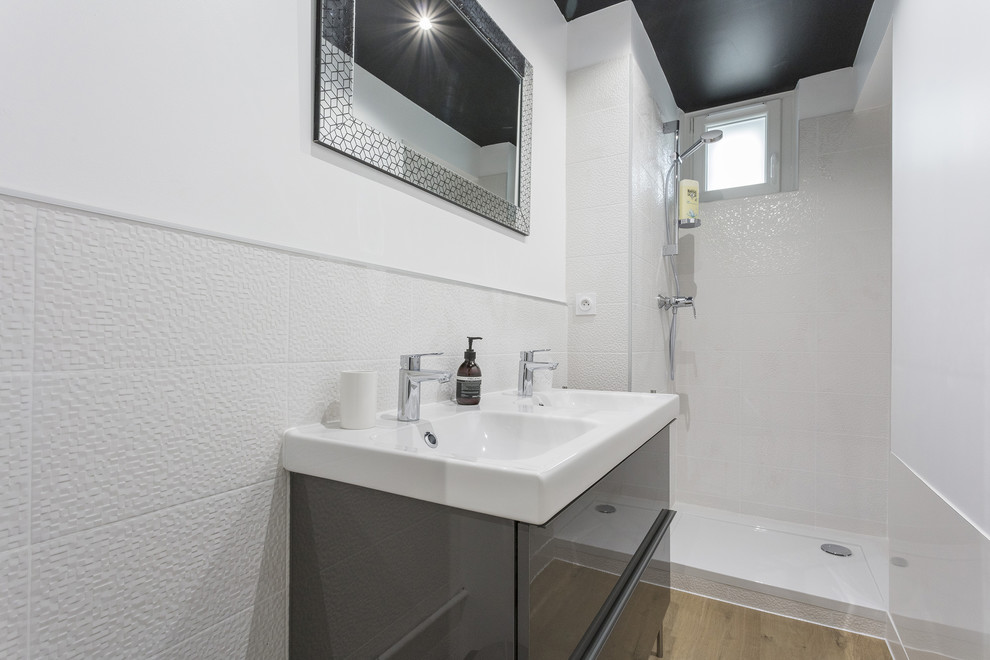 Inspiration pour une petite salle de bain urbaine avec un carrelage blanc, des carreaux de céramique, un mur blanc, parquet foncé, un plan vasque, un sol beige et une cabine de douche à porte battante.