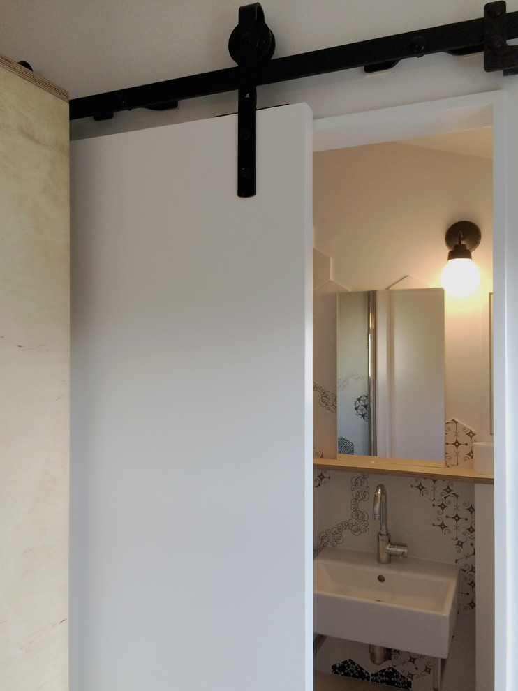Идея дизайна: маленькая ванная комната в скандинавском стиле с черными фасадами, душем без бортиков, инсталляцией, черно-белой плиткой, деревянным полом, душевой кабиной, подвесной раковиной, белым полом, белыми стенами и керамической плиткой для на участке и в саду
