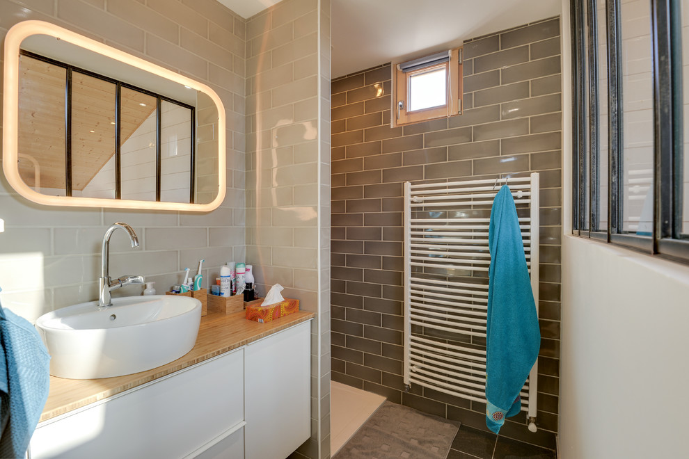 Inredning av ett nordiskt mycket stort brun brunt badrum, med släta luckor, vita skåp, våtrum, beige kakel, beige väggar, ett fristående handfat, träbänkskiva och med dusch som är öppen