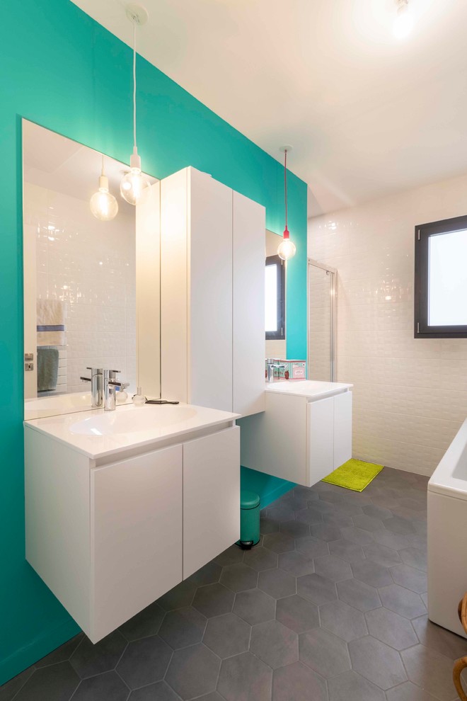 Cette image montre une douche en alcôve principale design avec un placard à porte plane, des portes de placard blanches, un carrelage blanc, un mur bleu, un lavabo intégré, un plan de toilette blanc et un sol gris.