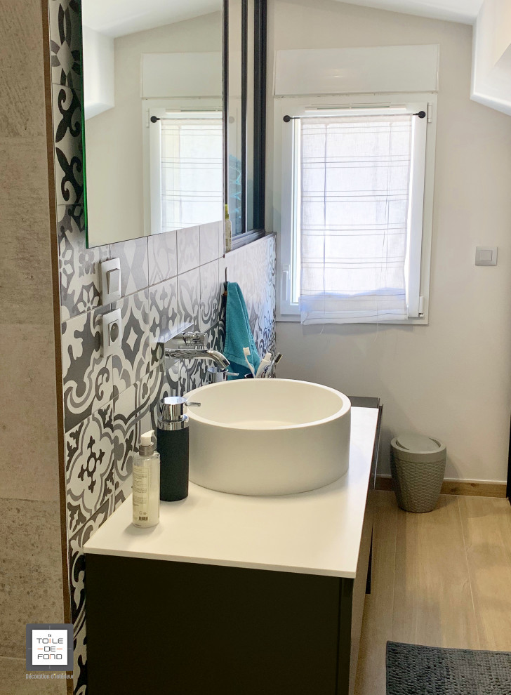 Bild på ett 60 tals vit vitt badrum, med ett fristående badkar, en kantlös dusch, en vägghängd toalettstol, svart och vit kakel, vita väggar, ett nedsänkt handfat, bänkskiva i akrylsten och med dusch som är öppen