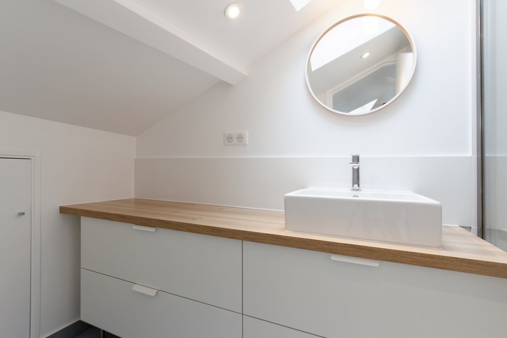 На фото: главная ванная комната в скандинавском стиле с плоскими фасадами, белыми фасадами, душем без бортиков, белой плиткой, керамической плиткой и столешницей из дерева