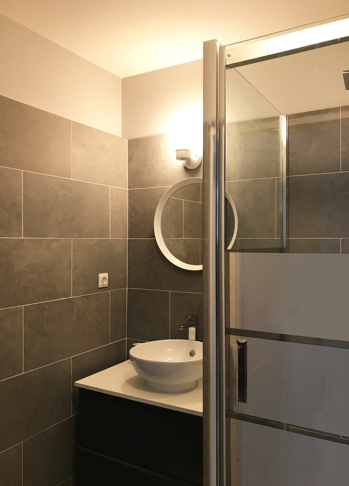 Small contemporary ensuite bathroom in Lyon with louvered cabinets, light wood cabinets, a built-in shower, a two-piece toilet, grey tiles, ceramic tiles, grey walls, ceramic flooring, a vessel sink, laminate worktops, grey floors and a hinged door.