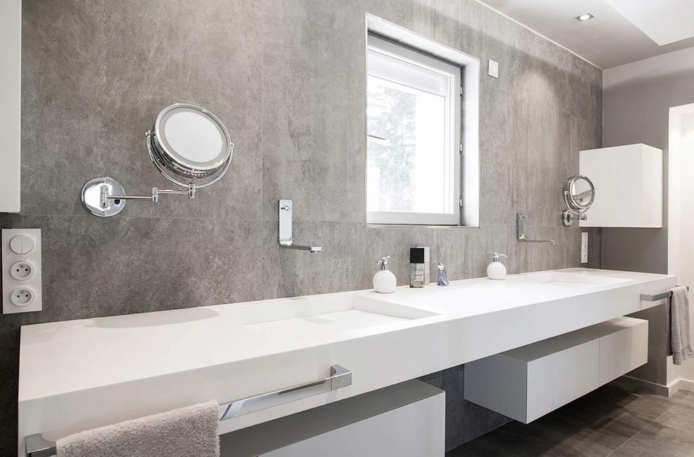 Ejemplo de cuarto de baño moderno grande con lavabo integrado, armarios con paneles lisos, puertas de armario blancas, baldosas y/o azulejos grises y paredes grises