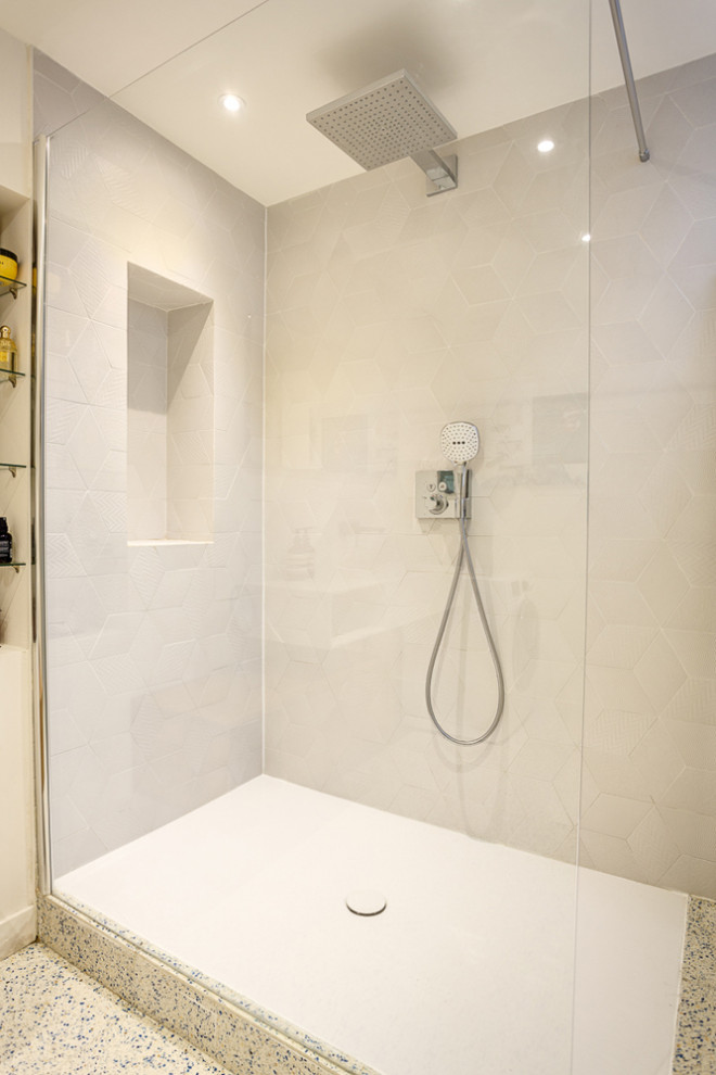 Пример оригинального дизайна: главная ванная комната среднего размера в стиле модернизм с плоскими фасадами, белыми фасадами, душем без бортиков, серой плиткой, керамической плиткой, белыми стенами, полом из терраццо, раковиной с несколькими смесителями, столешницей из искусственного камня, белым полом, открытым душем и белой столешницей