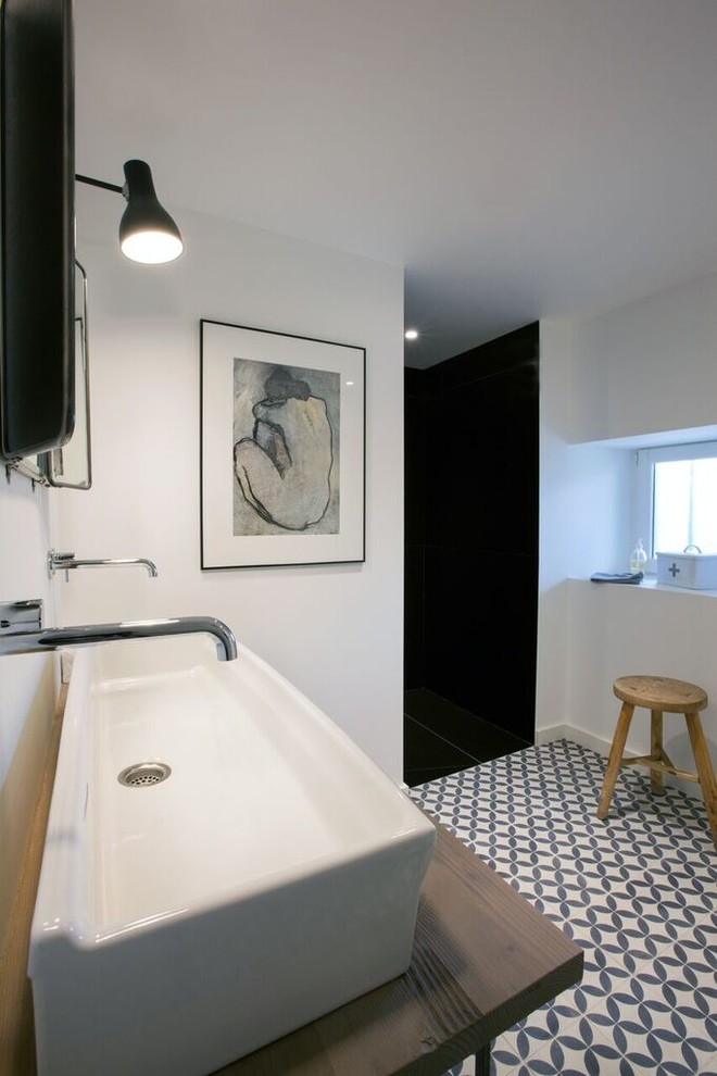 Inredning av ett industriellt stort brun brunt en-suite badrum, med vita väggar, cementgolv, ett avlångt handfat, träbänkskiva och blått golv