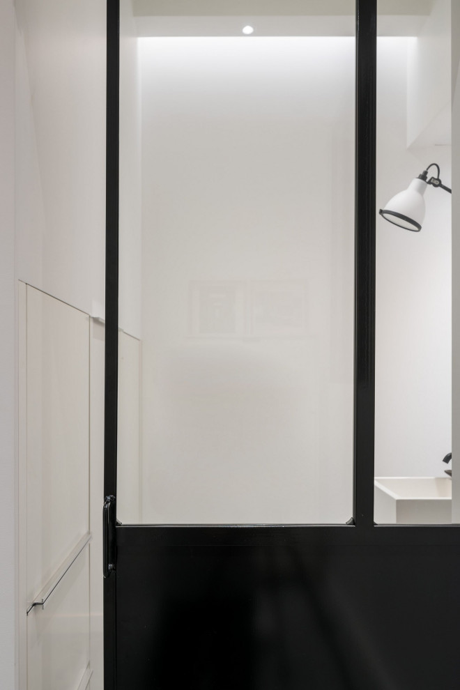 Cette photo montre une petite salle d'eau moderne avec un placard à porte affleurante, des portes de placard blanches, une douche à l'italienne, WC suspendus, un carrelage beige, des carreaux de céramique, un mur blanc, un lavabo suspendu, un plan de toilette en béton, un sol gris, une cabine de douche à porte battante et un plan de toilette blanc.
