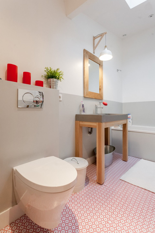 Imagen de cuarto de baño principal contemporáneo de tamaño medio con bañera encastrada, sanitario de pared, paredes grises y lavabo tipo consola