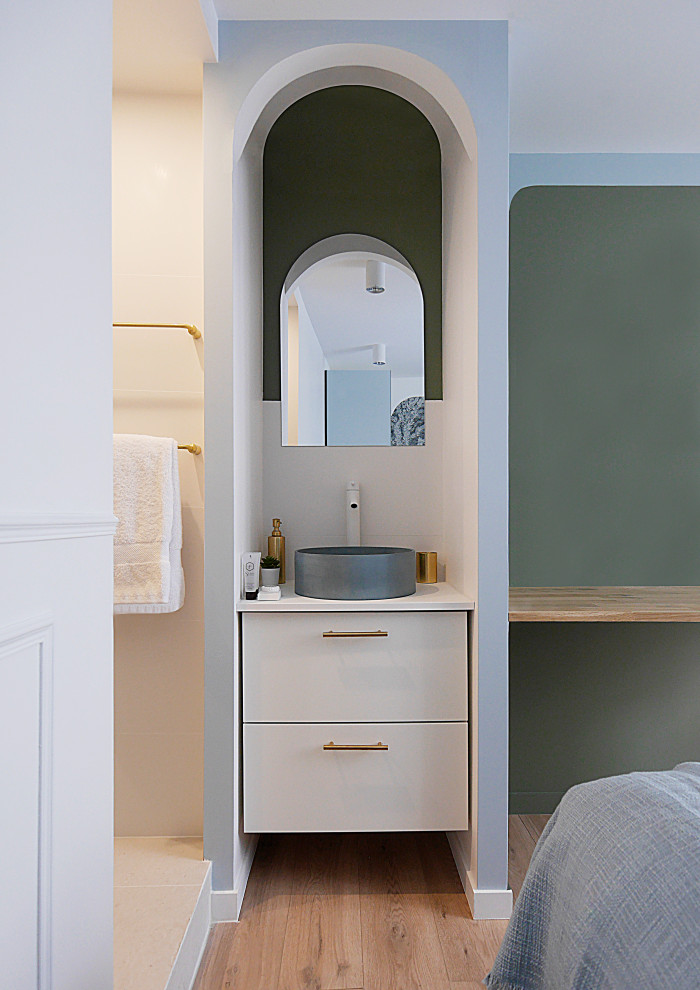 Bild på ett litet funkis blå blått en-suite badrum, med släta luckor, vita skåp, vit kakel, keramikplattor, vita väggar, ljust trägolv, ett fristående handfat, bänkskiva i betong och beiget golv